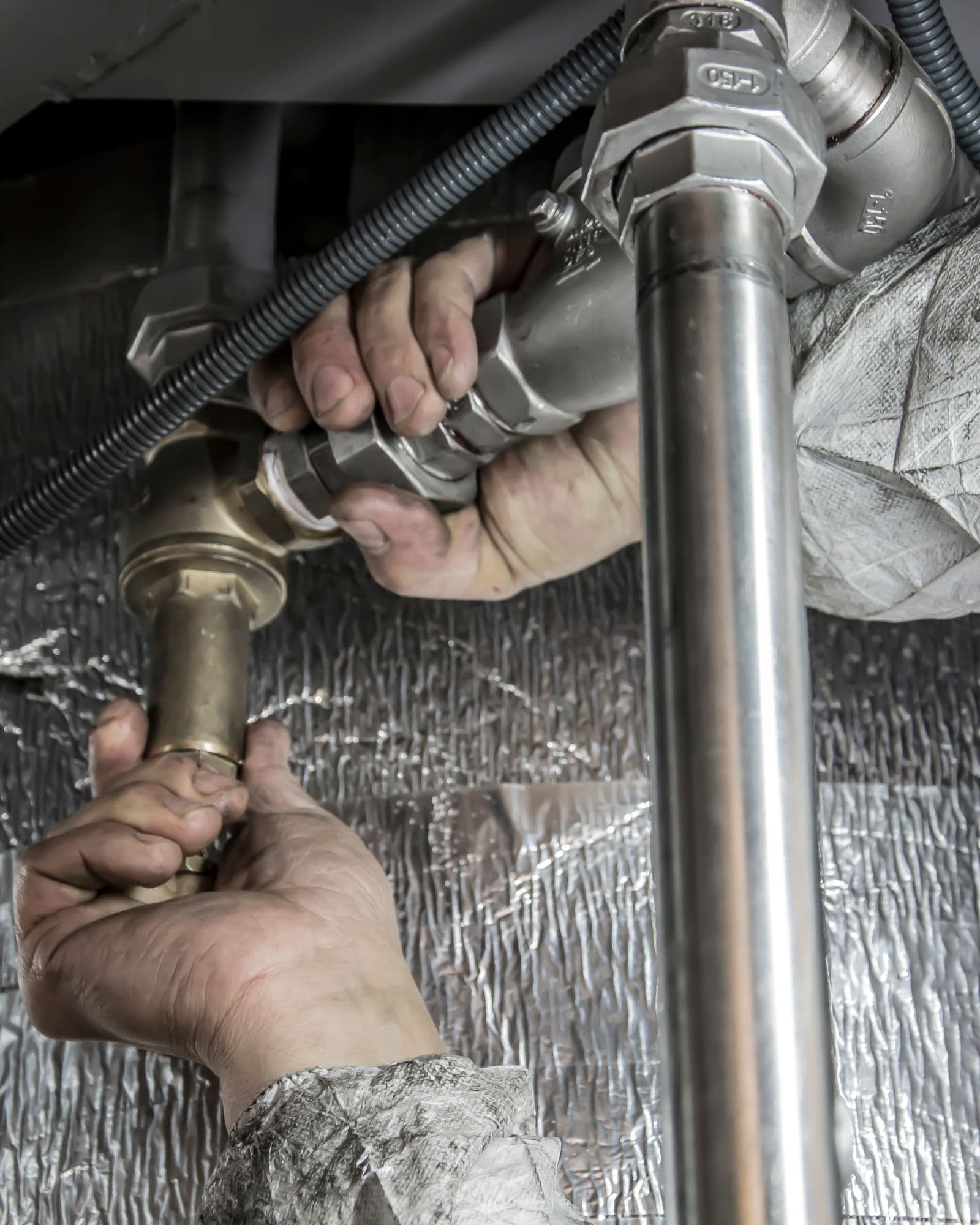 Plumber fitting brass and steel supply pipes on a commercial job